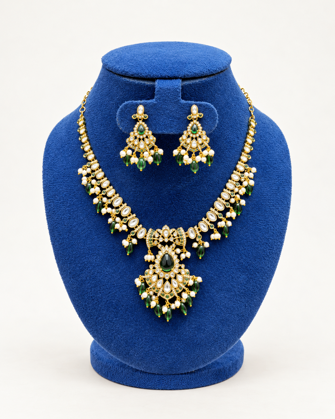 Kaveri kundan style beaded necklace set with earrings in green on a blue velvet display stand