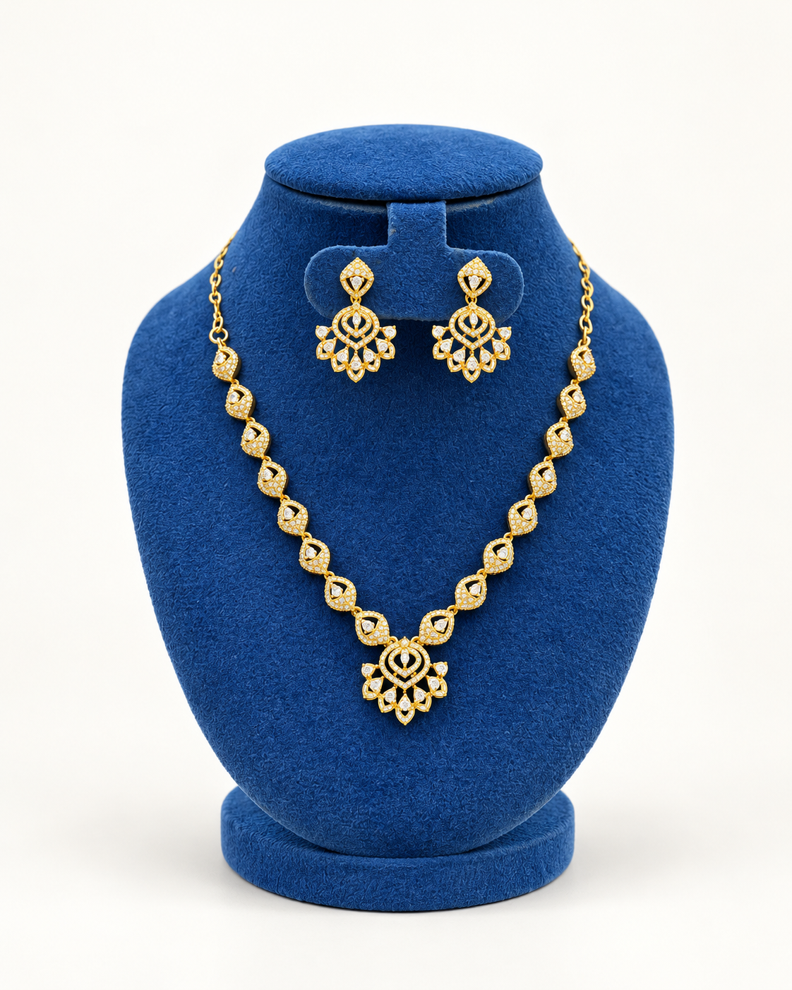 Kaveri leaf link floral drop necklace set with earrings in gold on a blue velvet display stand