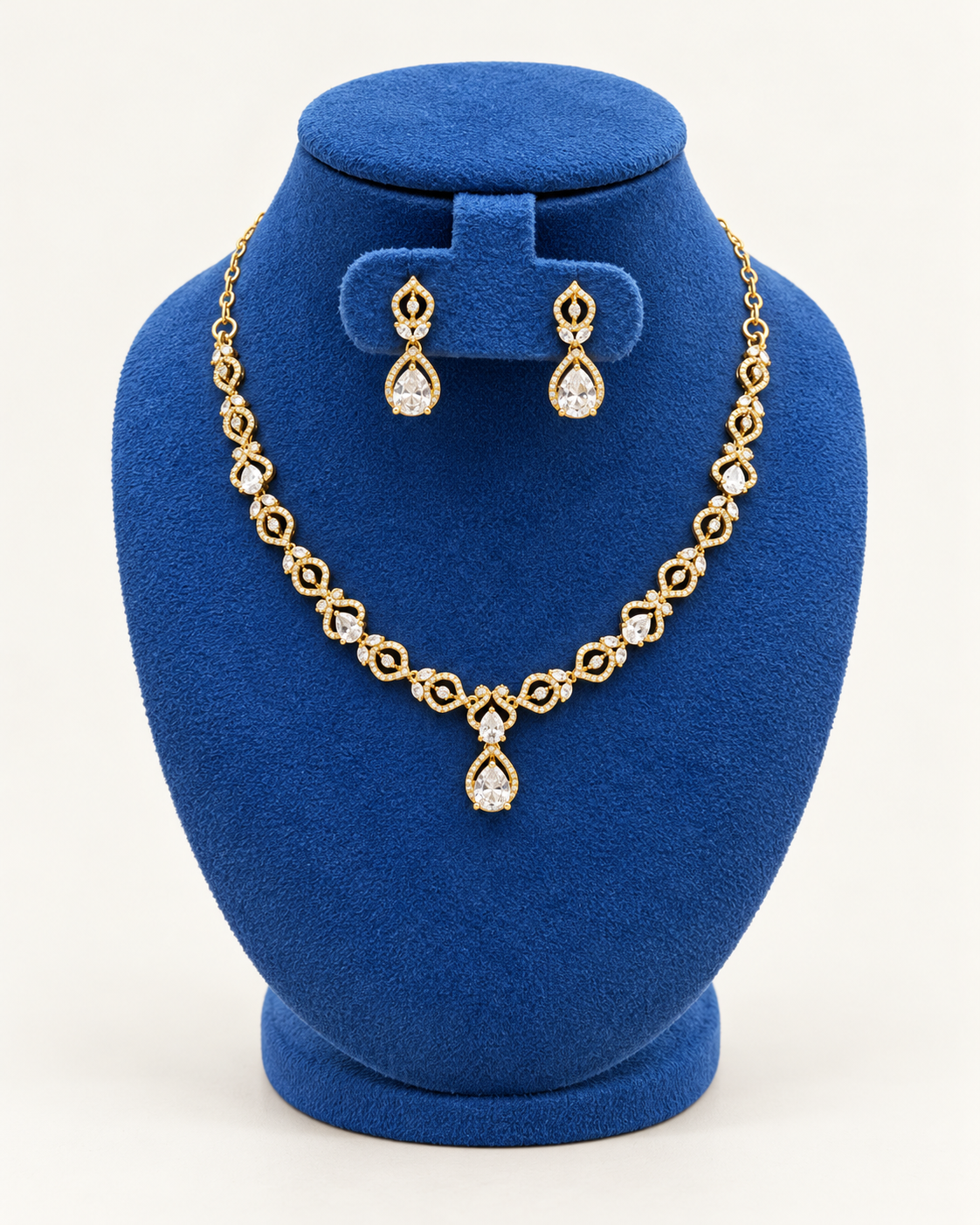 Kaveri double leaf teardrop necklace set with earrings in clear on a blue velvet display stand