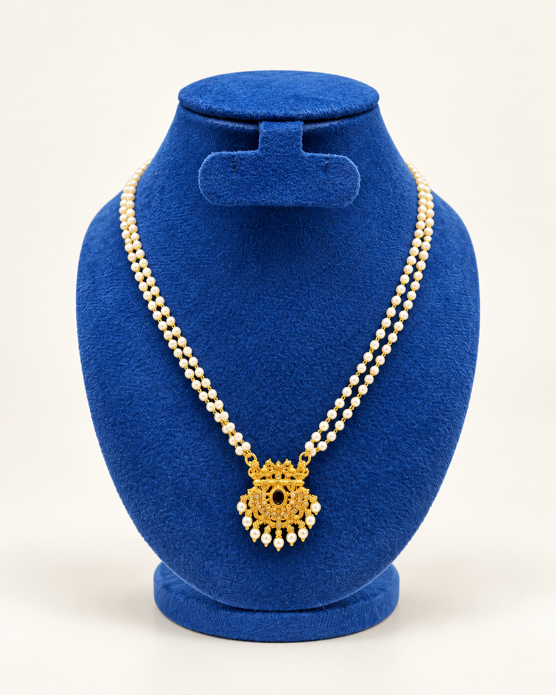 Kaveri double strand pearl temple pendant necklace in gold on a blue velvet display stand