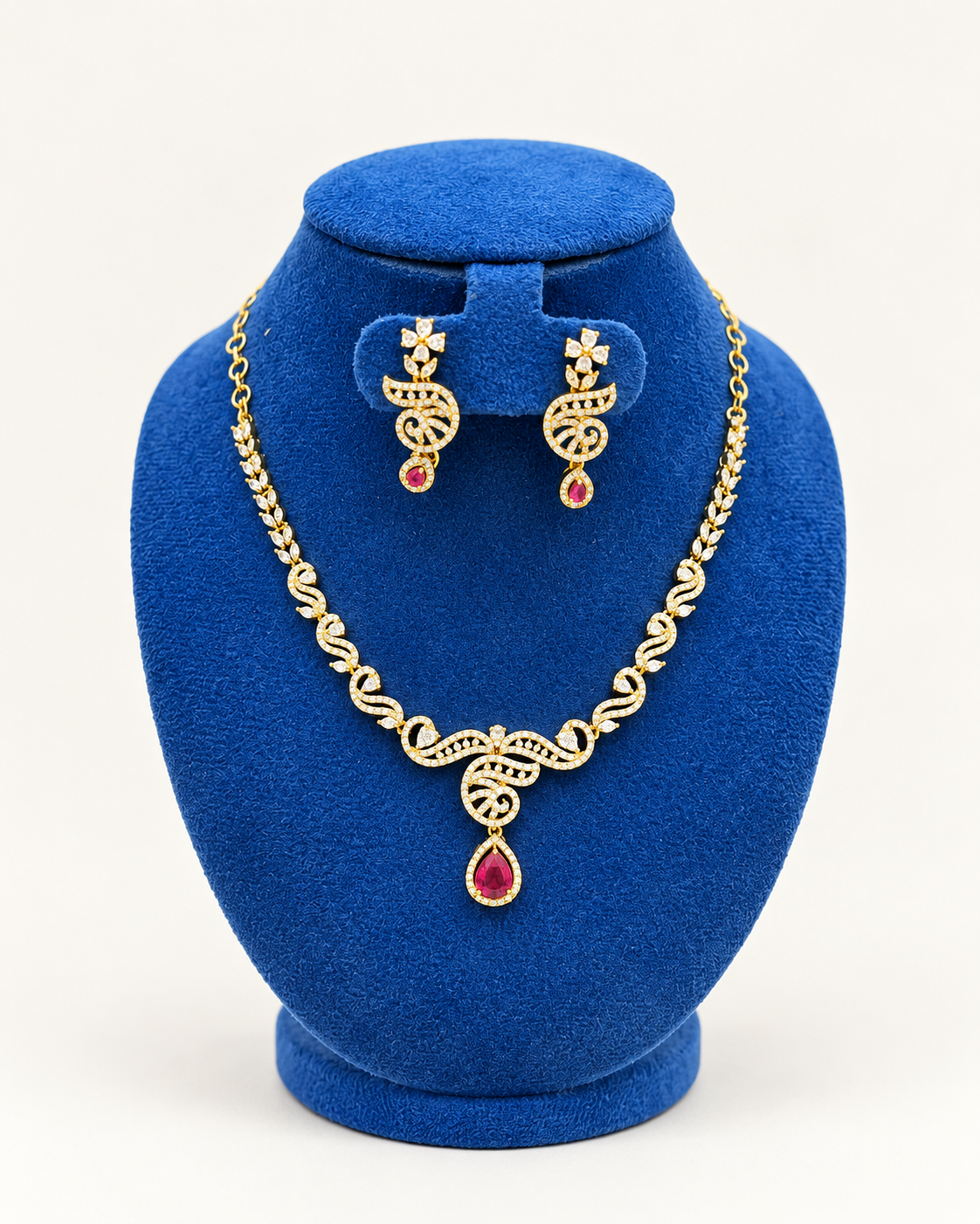 Kaveri swirl leaf pendant necklace set with earrings in maroon on a blue velvet display stand