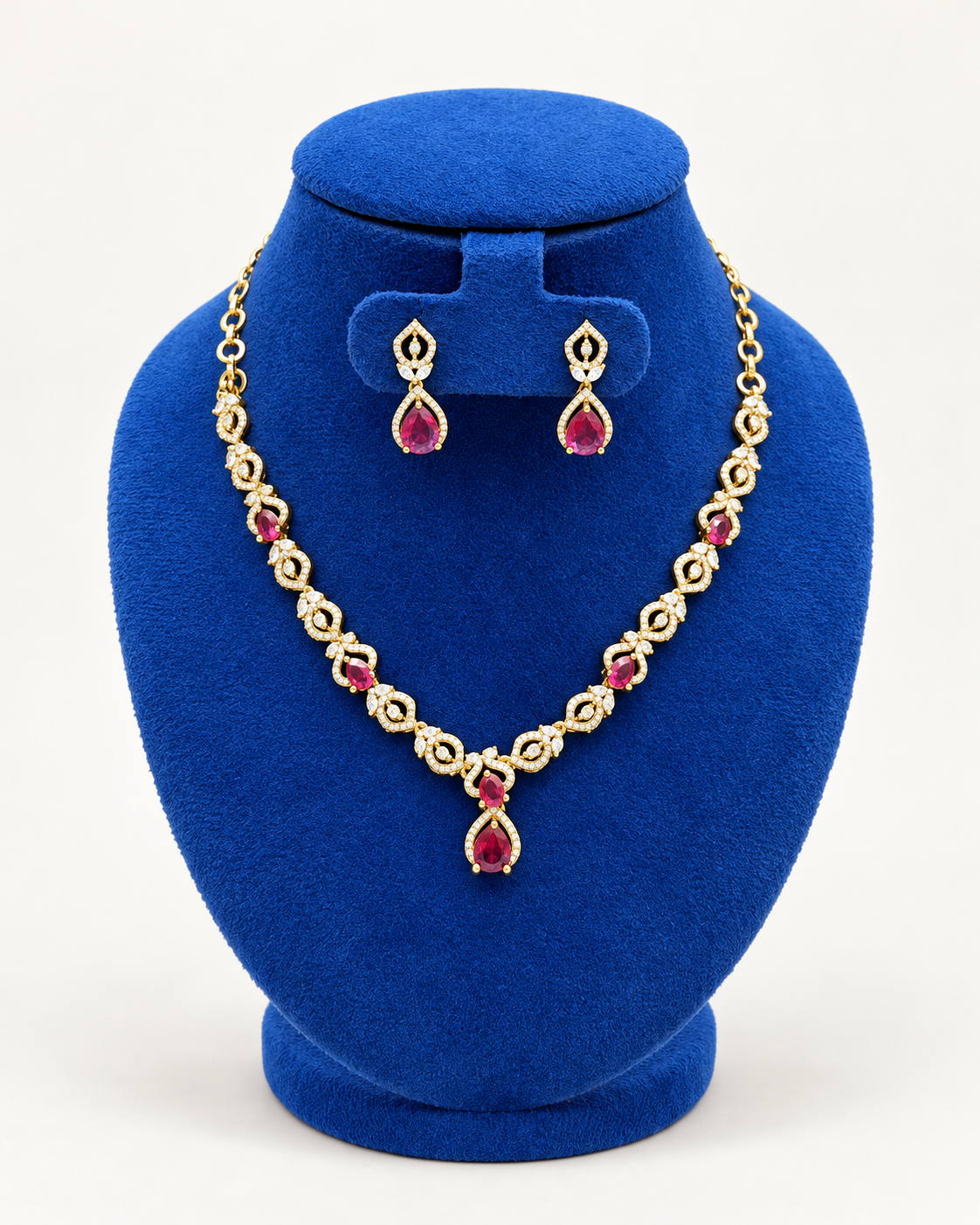 Kaveri double leaf teardrop necklace set with earrings in maroon on a blue velvet display stand