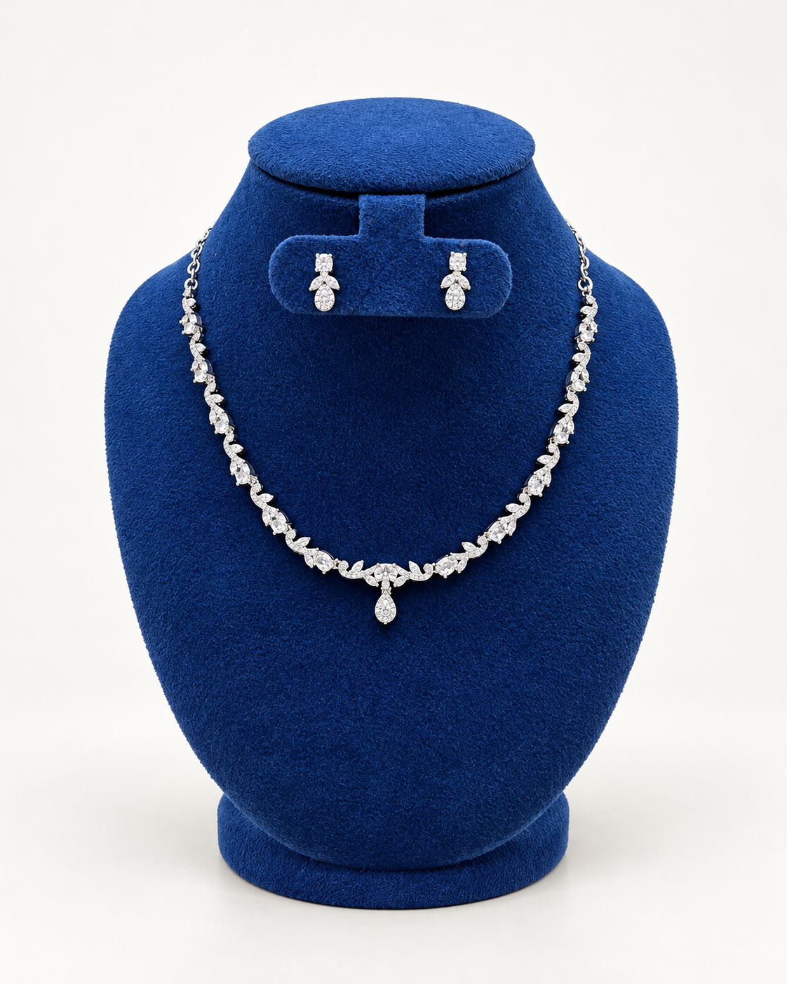 Kaveri leaf vine necklace set with petite earrings in clear on a blue velvet display stand