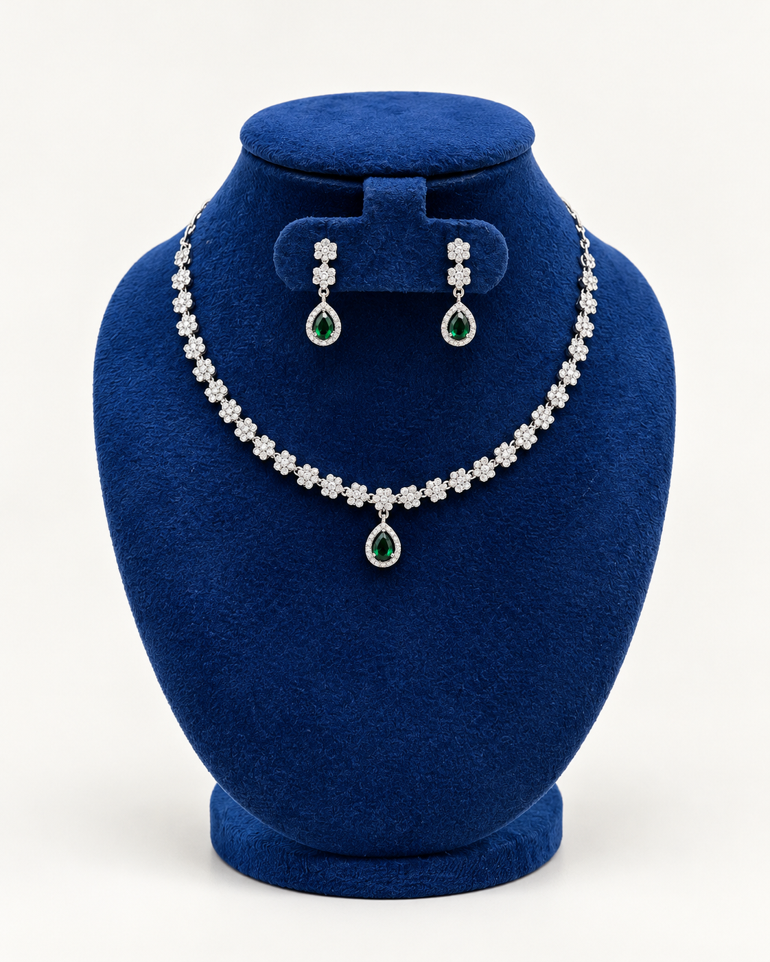 Kaveri flower line teardrop necklace set with earrings in green on a blue velvet display stand
