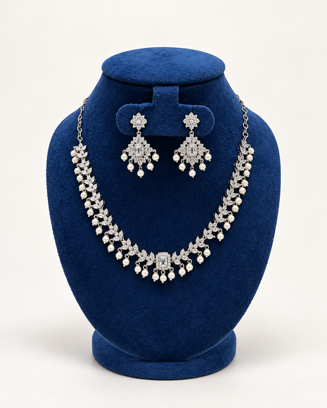 Kaveri double row pearl fringe necklace set with earrings in clear on a blue velvet display stand