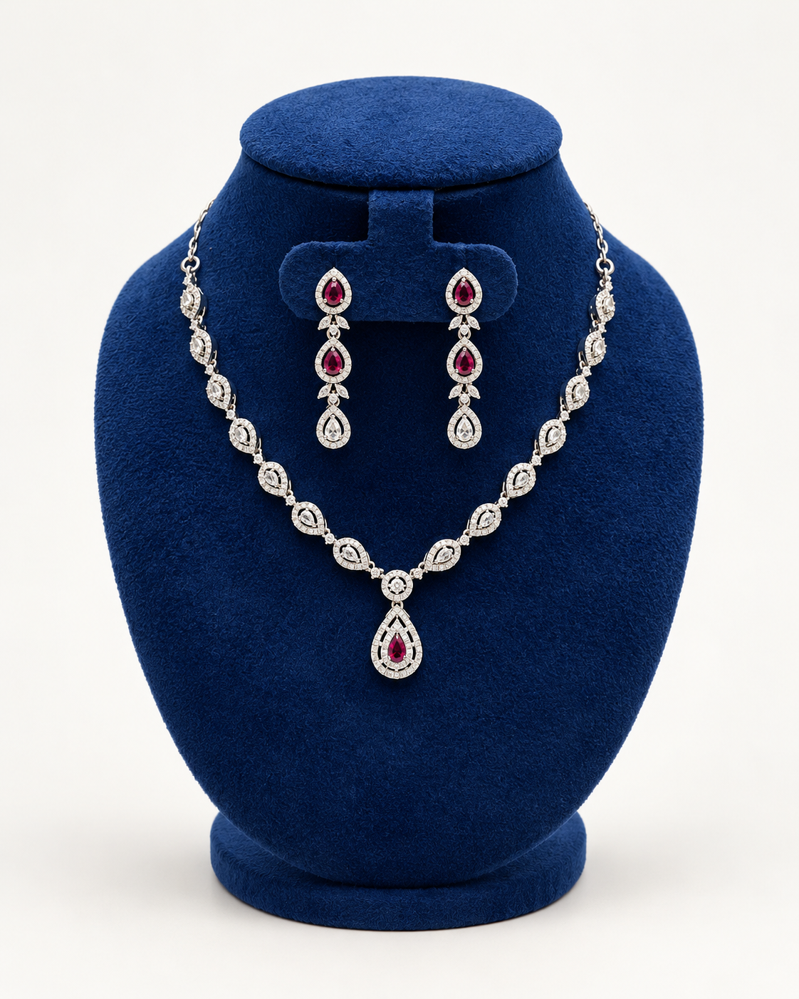 Kaveri leaf halo teardrop necklace set with earrings in maroon on a blue velvet display stand
