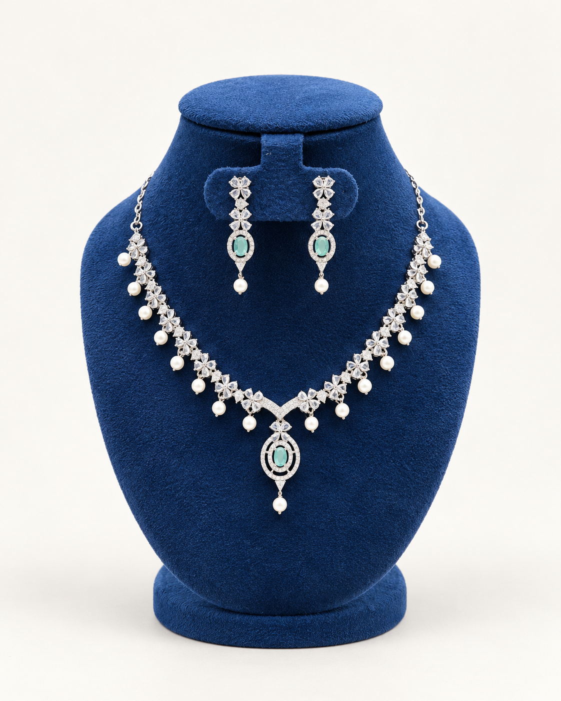 Kaveri oval stone pearl fringe necklace set with earrings in green on a blue velvet display stand