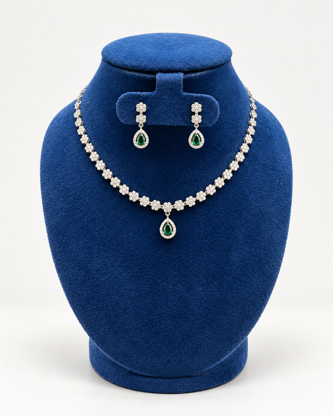 Kaveri flower line teardrop necklace set with earrings in green on a blue velvet display stand