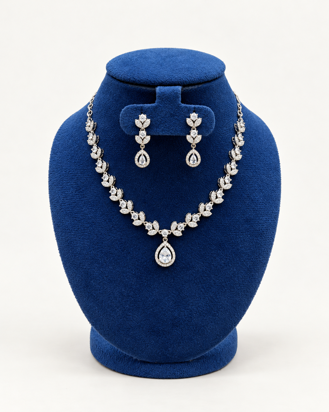 Kaveri petal cluster necklace set with drop earrings in clear on a blue velvet display stand