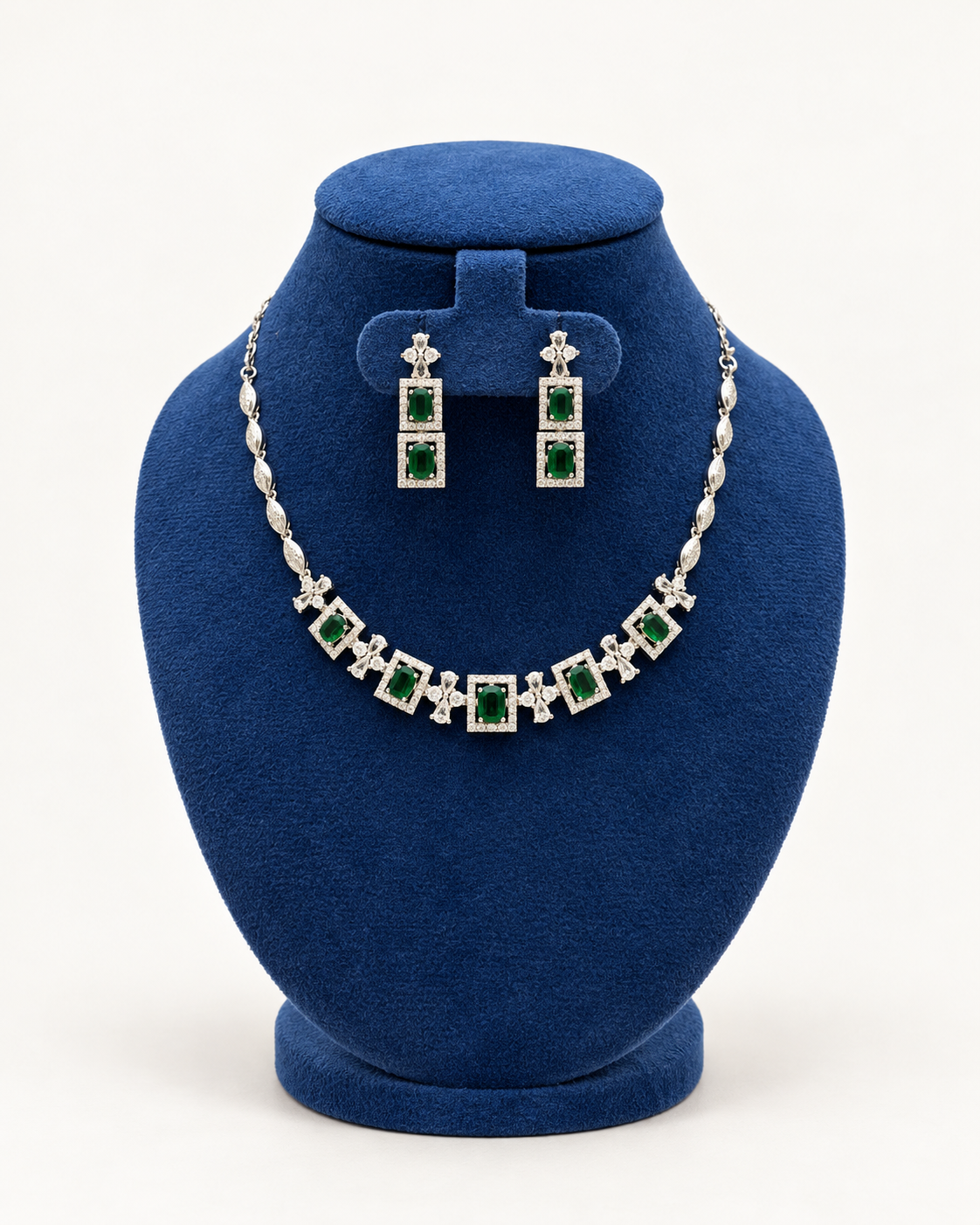 Kaveri square halo necklace set with long earrings in green on a blue velvet display stand